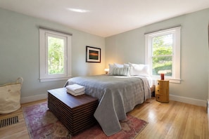 A bedroom with a bed, bedside tables, a window, and a view of greenery. - The Woodstock Bungalow | Walk to the Village (Woodstock)
