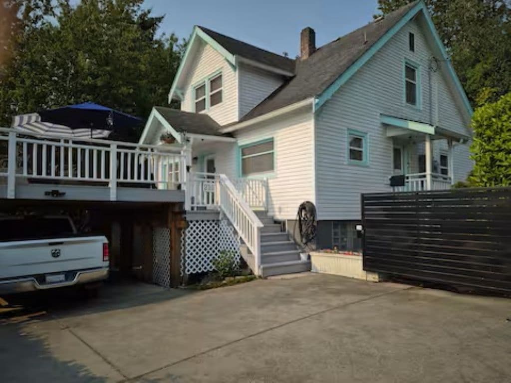 Une maison à deux étages avec un porche à l’avant, un garage et une allée.