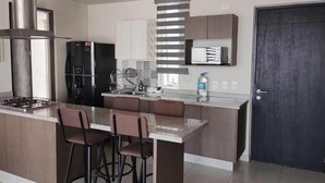 Una cucina moderna con isola centrale, sgabelli da bar, piano cottura integrato e forno a microonde.