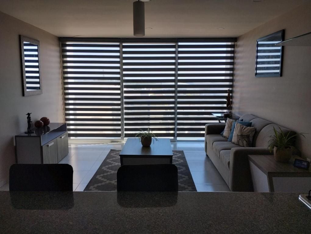 A modern living room with a sofa, coffee table, and a dining area with chairs.