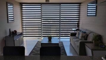 A modern living room with a sofa, coffee table, and a dining area with chairs.