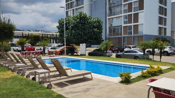 Un albergo con piscina, area salotto esterna e parcheggio.