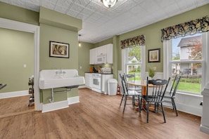 A kitchen with a white sink, white cabinets, a dining table with chairs, and a view of the outside. - Doyle House 3.9 miles from Cooperstown Dreams Park (Milford)