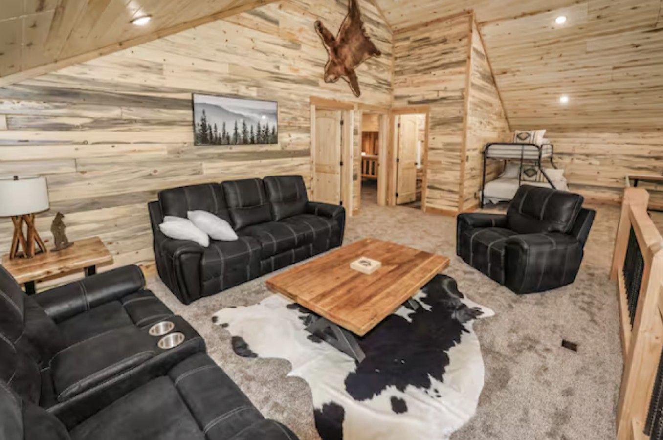 A log cabin interior with a sofa set, a coffee table, and a cowhide rug.