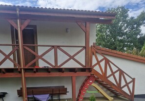 Un edificio con balcón, puerta y un tobogán pequeño.