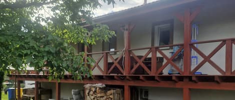 Un edificio con un porche cubierto, mobiliario exterior y una pila de leña.
