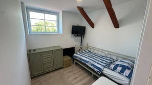 Un dormitorio con cama, televisor, ventana y armario.