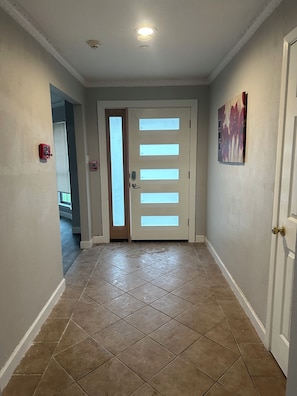 A hallway with a door, a fire alarm, and a window. - Private Room in a Spacious, Budget-Friendly Home (Keller)