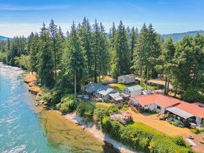 A coastal property with multiple buildings, a beach, and dense forest.