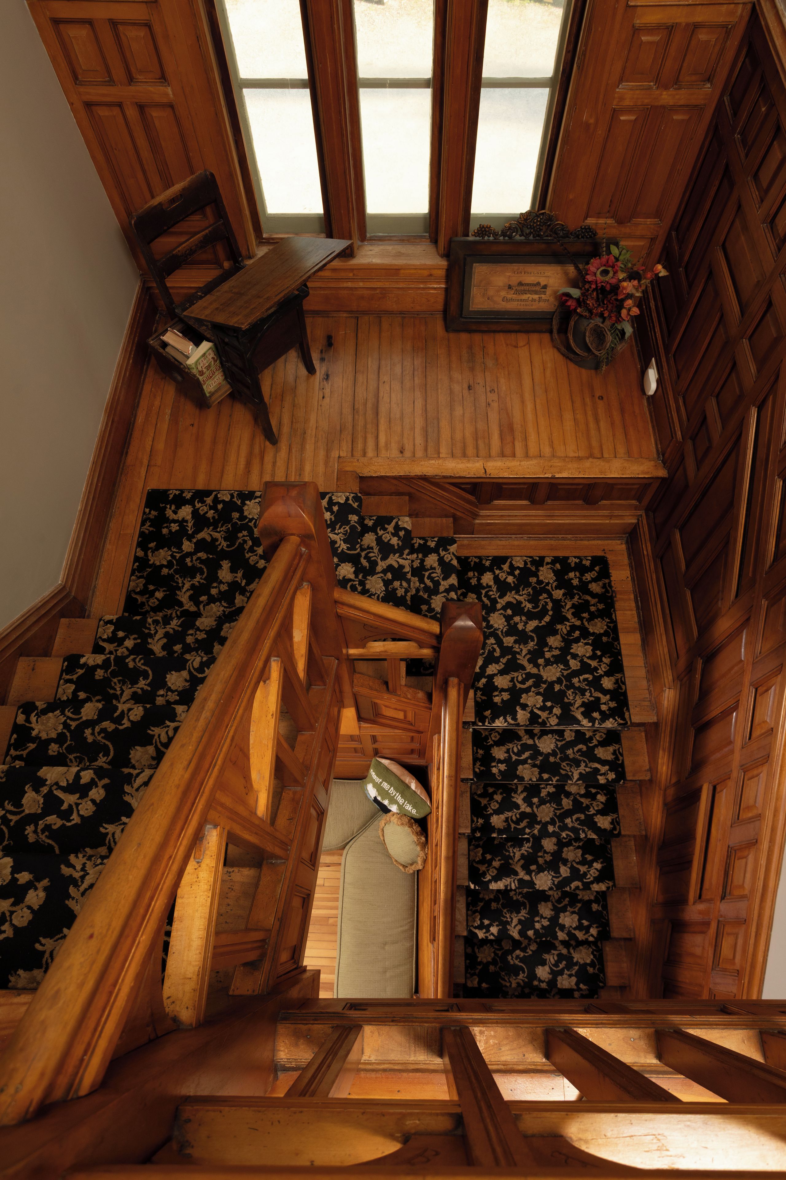 A wooden staircase leading to a loft area with a view of the outdoors.