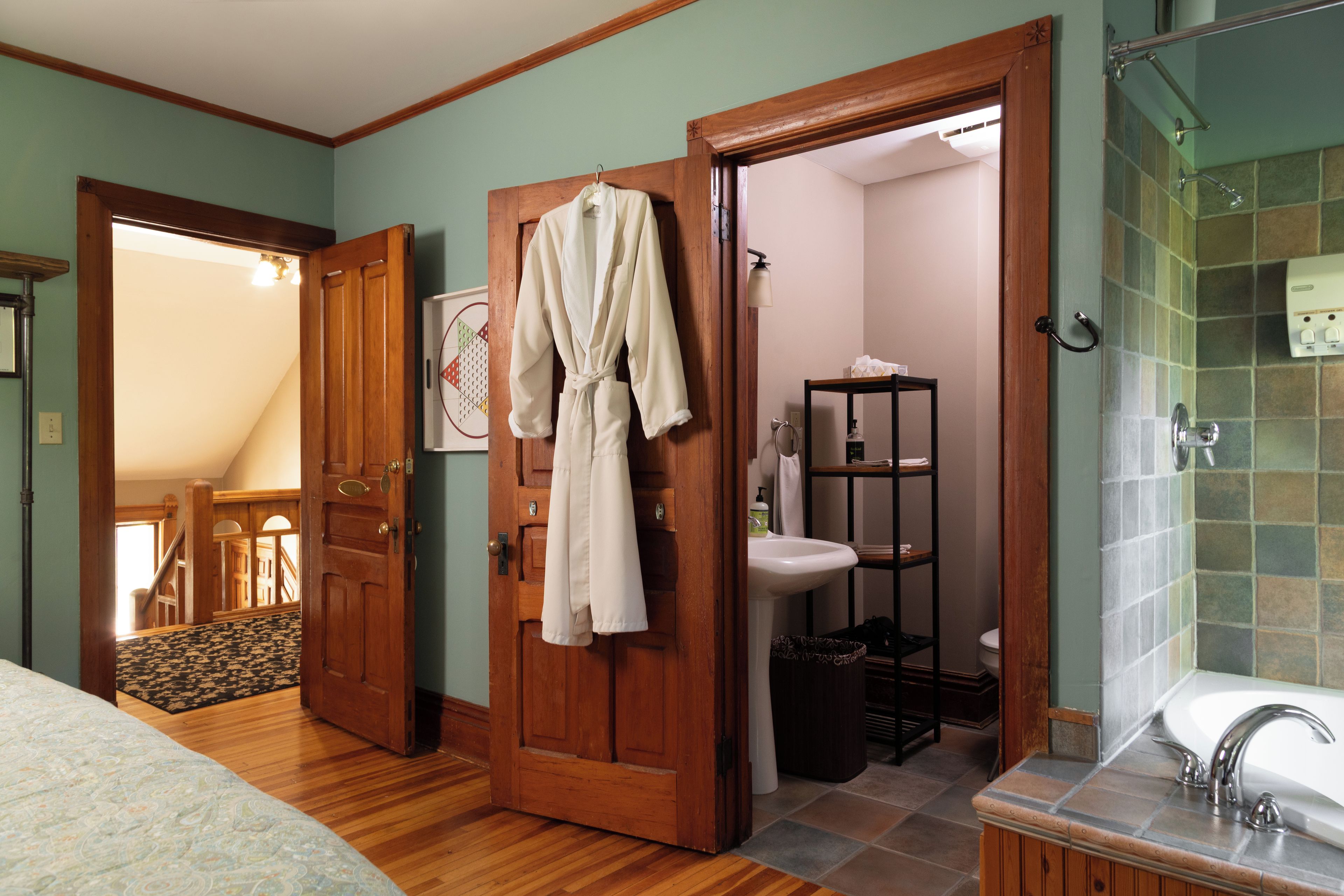 A bathroom with a wooden door, a sink, a mirror, and a shower area.