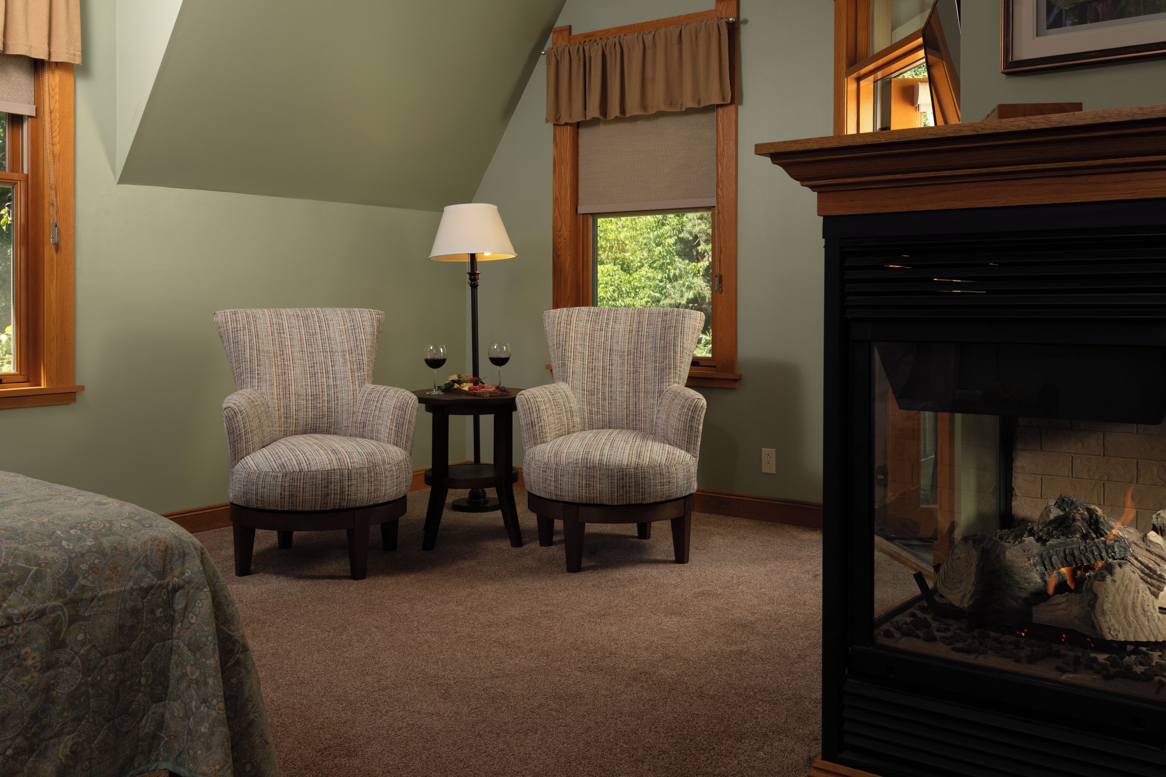 Una habitación con dos sillones tapizados, una mesita con lámpara y una chimenea.