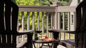 A dining area with two chairs and a small table with a glass of red wine and a plate of food.