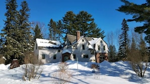 A large, two-story house with a snow-covered roof and a chimney, surrounded by evergreen trees. - Pinehurst Inn - Luxury Bayfield Hotel (Bayfield)