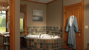 A bathroom with a bathtub, a sink, and a robe hanging on the door. - Pinehurst Inn - Luxury Bayfield Hotel (Bayfield)