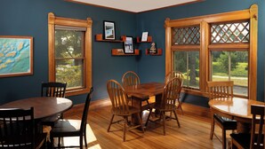 A dining room with a wooden table and chairs, large windows with lattice designs, and wall-mounted shelves with framed pictures and awards. - Pinehurst Inn - Luxury Bayfield Hotel (Bayfield)