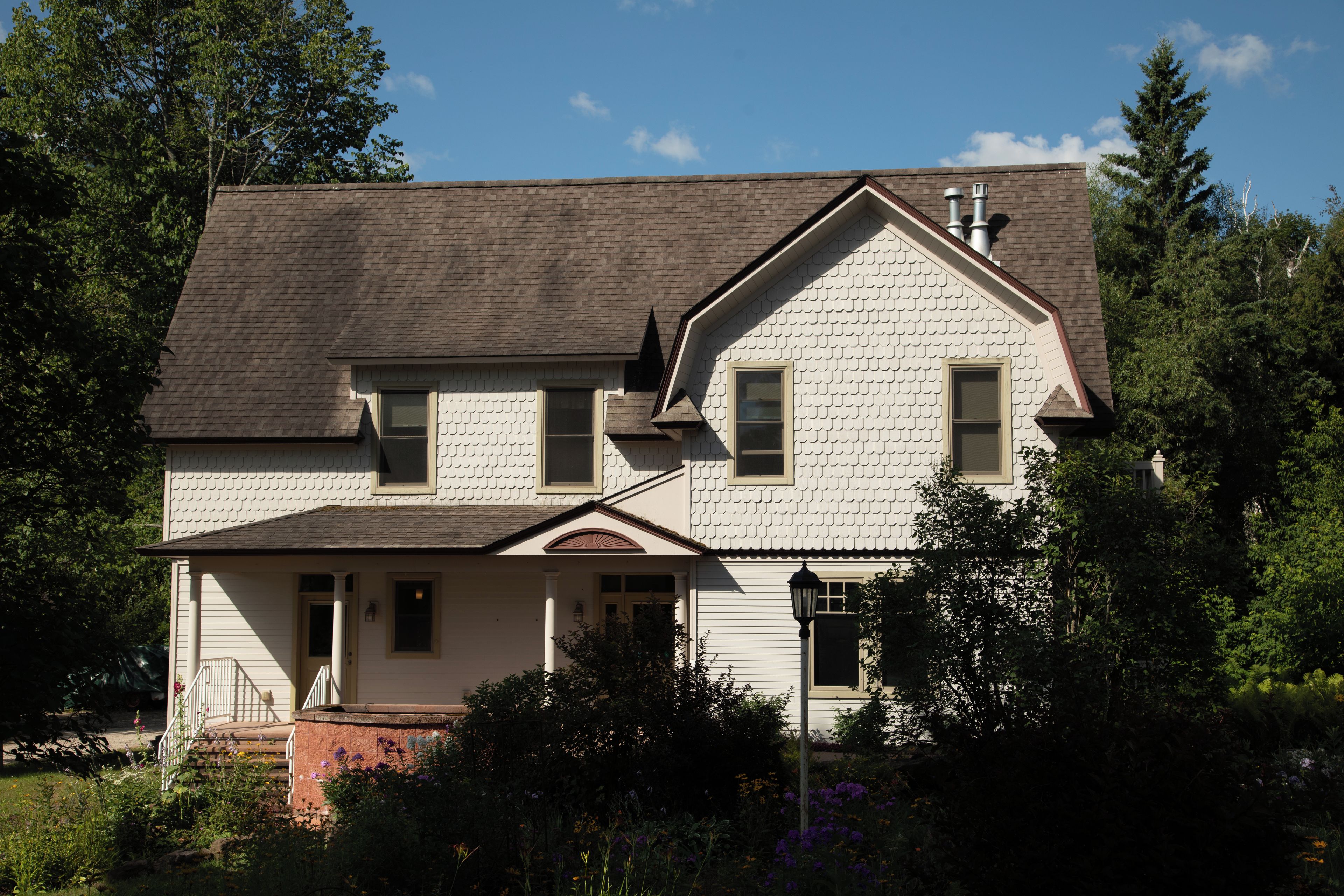A two-story house with a gabled roof, a front porch, and a chimney.
