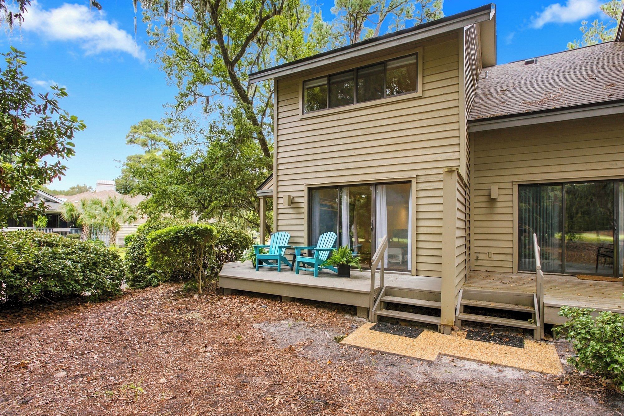 Azure chairs pop against the timber siding of this quiet back deck, where mossy oaks offer a cooling canopy. Afternoon glow filters through the leaves, creating a peaceful spot to breathe in the forest air from your private outdoor escape.
