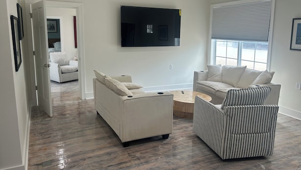 A modern living room with a flat-screen TV mounted on the wall, a sofa, a striped armchair, and a coffee table. - Waterfront luxury with boat dock accessibility (Morehead City)