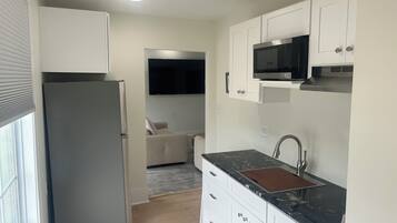 A compact kitchen with a refrigerator, microwave, and sink.