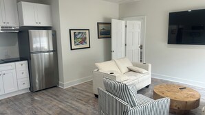A modern kitchen with stainless steel appliances, a dining area with a striped chair, and a flat-screen TV mounted on the wall. - Waterfront luxury with boat dock accessibility (Morehead City)