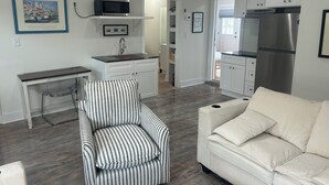 A compact living space with a kitchenette, a striped armchair, a white sofa, and a framed picture on the wall. - Waterfront luxury with boat dock accessibility (Morehead City)