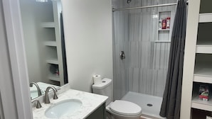 A bathroom with a marble sink, a toilet, a shower with a glass door, and a towel rack. - Waterfront luxury with boat dock accessibility (Morehead City)