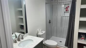 A bathroom with a marble sink, a toilet, a shower with a glass door, and a towel rack.