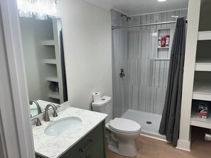 Ein Badezimmer mit Marmorwaschtisch, Toilette, Dusche mit Glastür und Handtuchhalter.