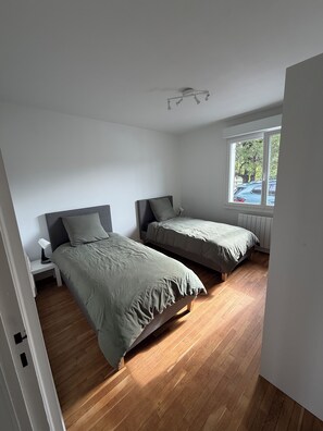Et soveværelse med to senge, et vindue og en loftlampe.