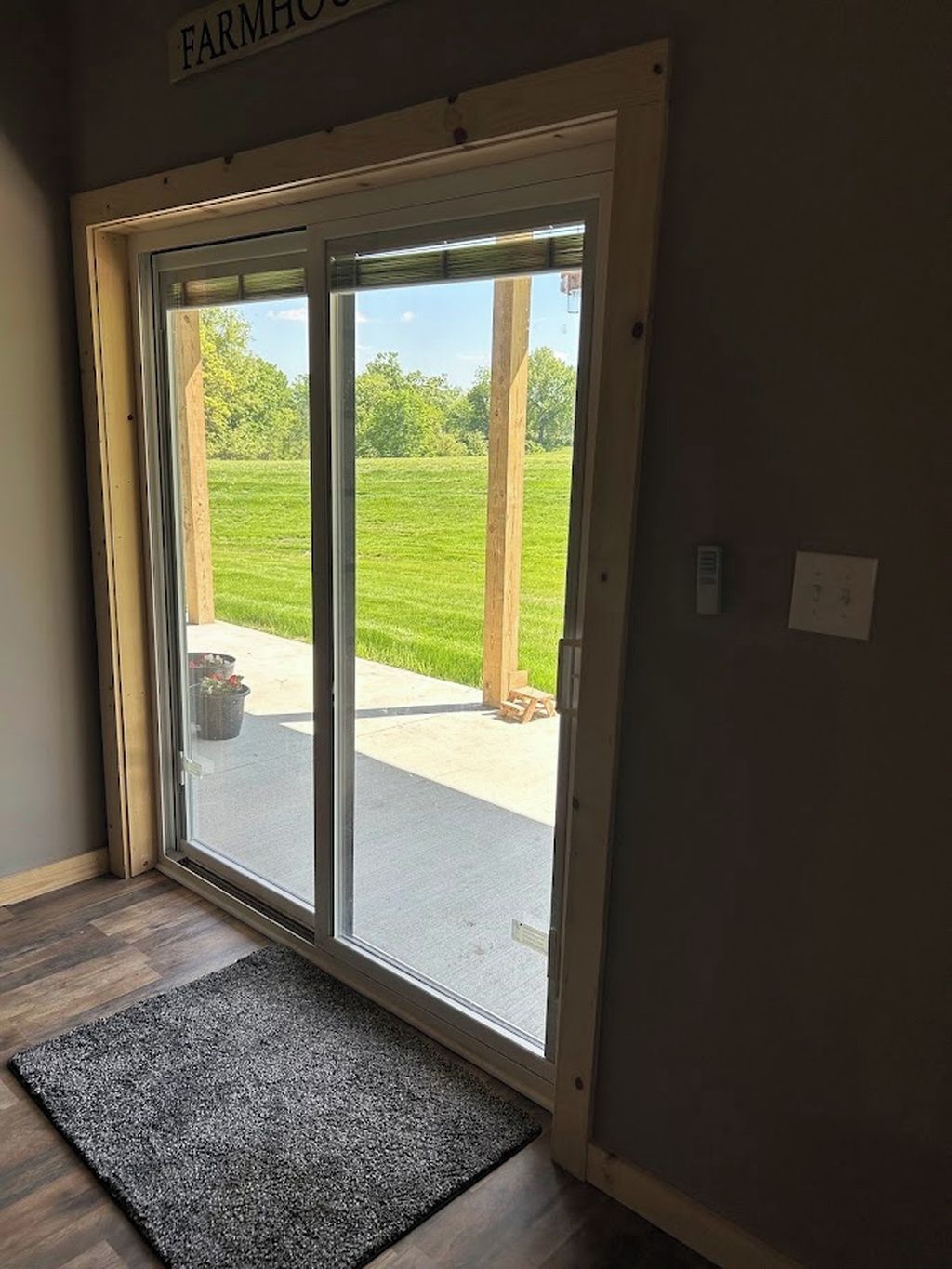 A door with a view of a green field and a wooden structure outside.