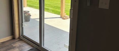 A door with a view of a green field and a wooden structure outside.