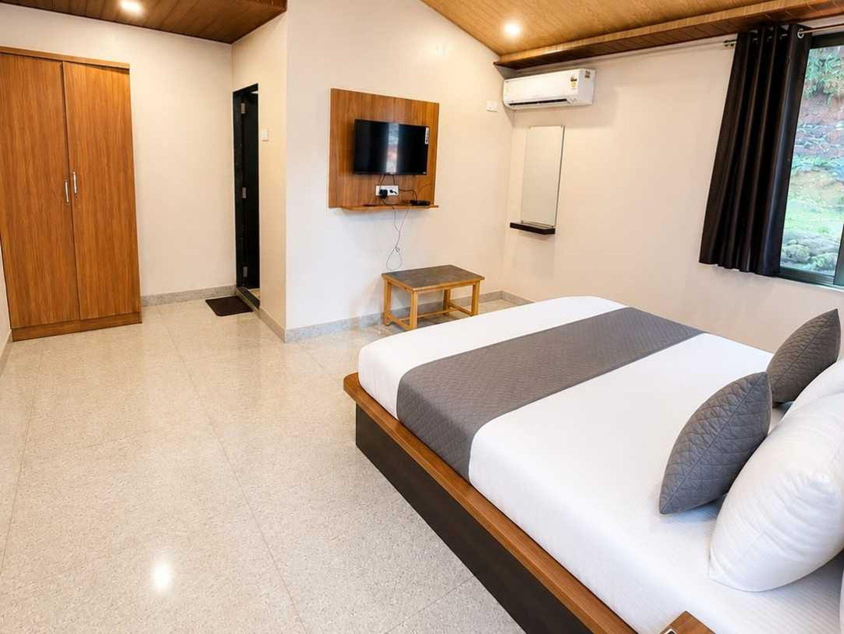 Un dormitorio con cama, televisión montada en la pared, aire acondicionado y armario.
