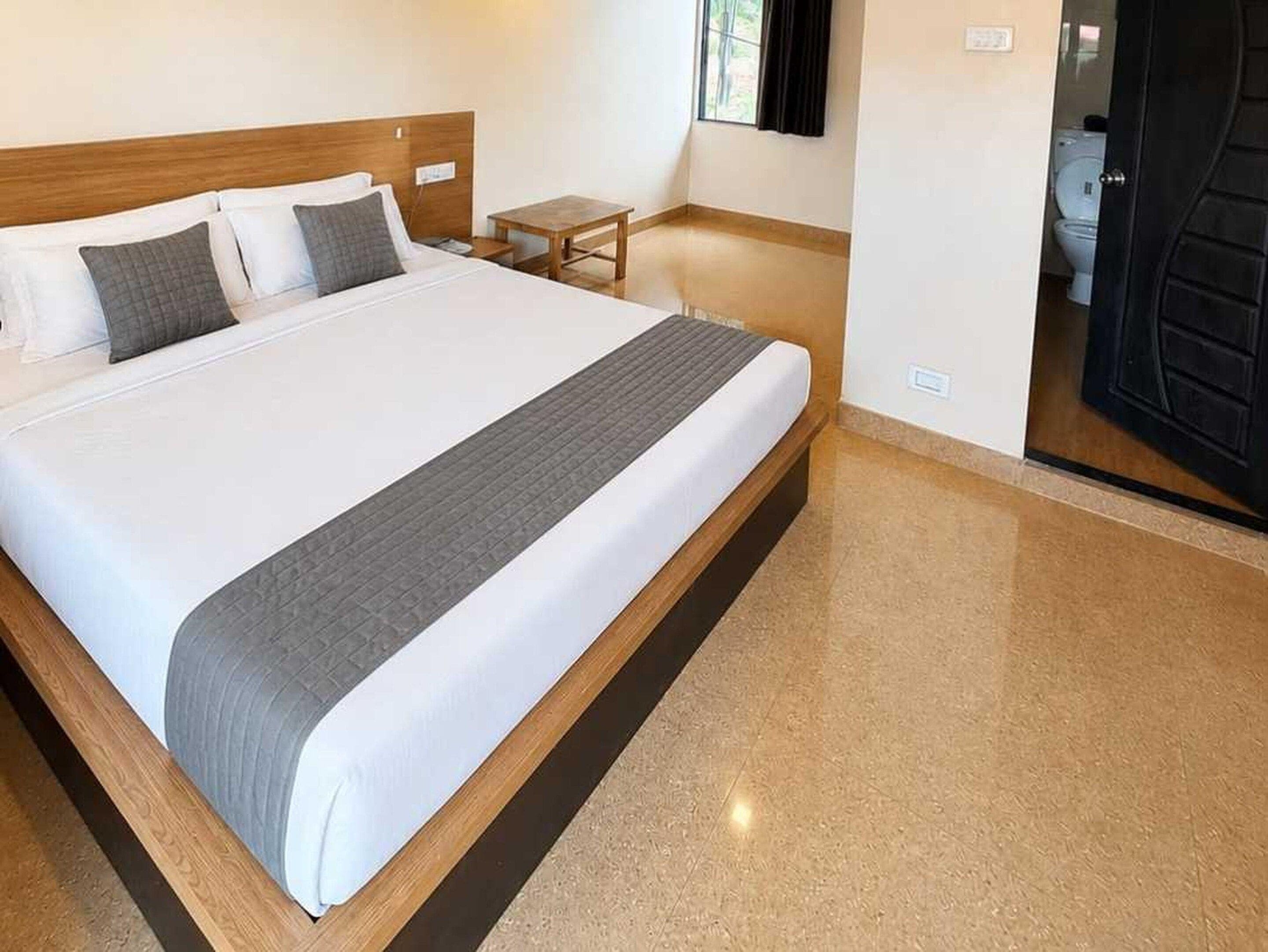 A hotel room with a large bed, a small table, and a view of the bathroom.