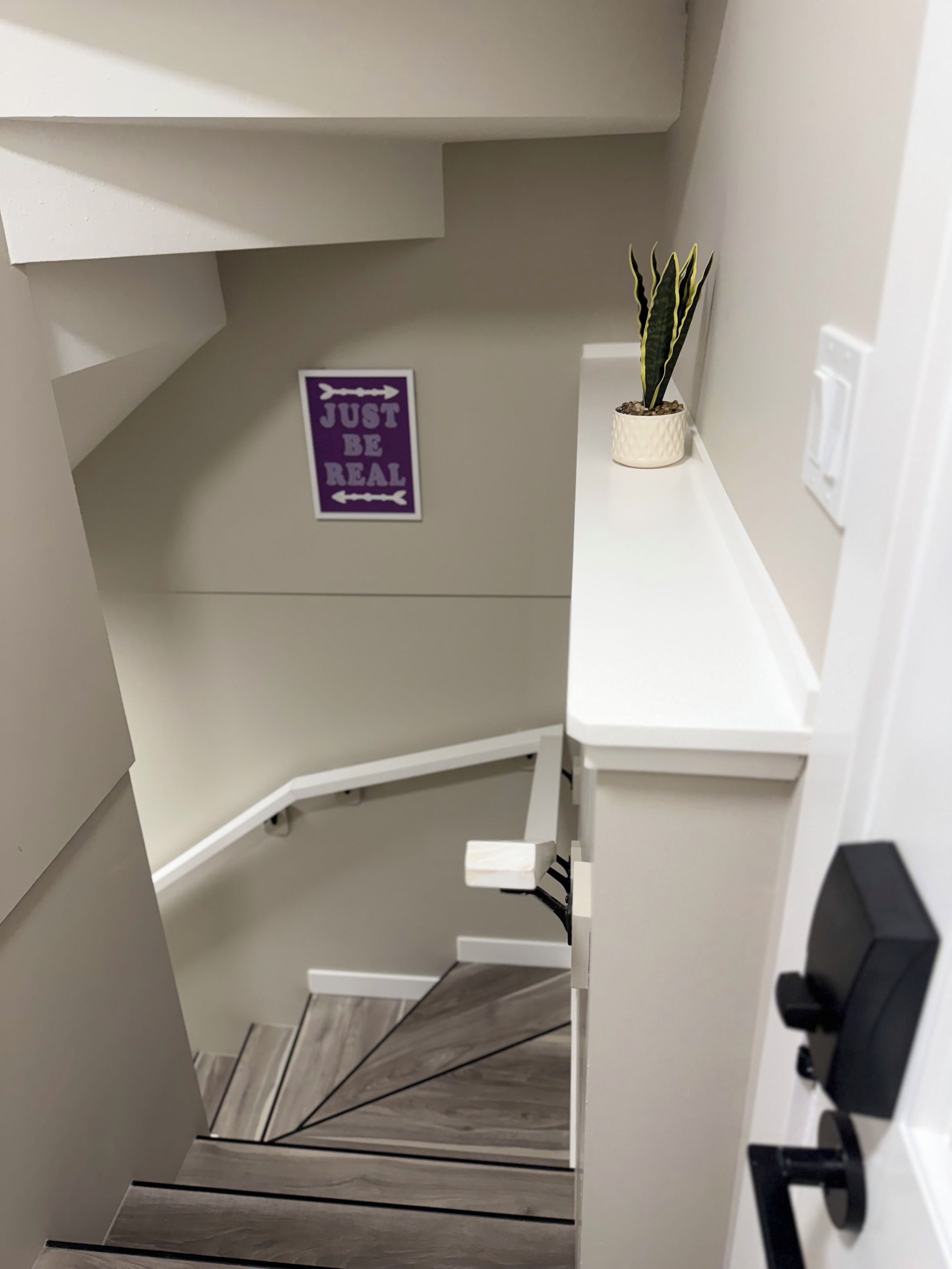 Eine Treppe mit einem Schild an der Wand, auf dem 'JUST BE REAL' steht.