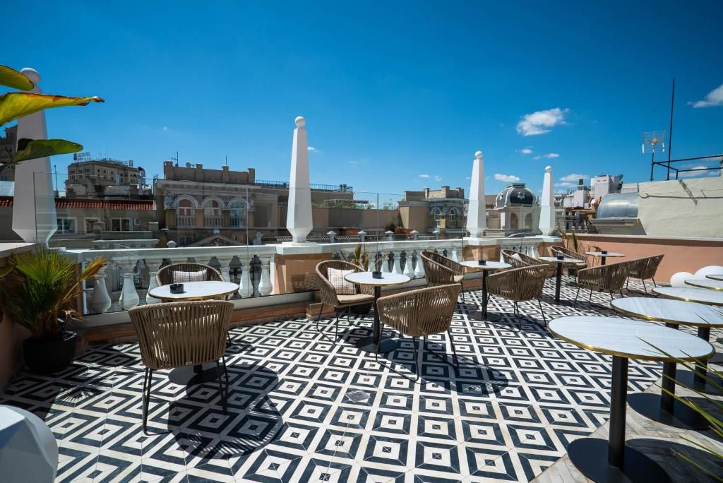 Terraza en la azotea con suelo estampado, mobiliario exterior y vistas a la ciudad.