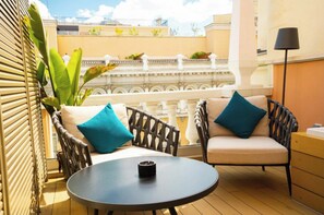 Ein Balkon mit Korbmöbeln, einem runden Tisch und einem Blumentopf.