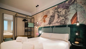 Una habitación de hotel con una cama grande, un espejo, una pared con un mural detallado y una mesita con una vela.
