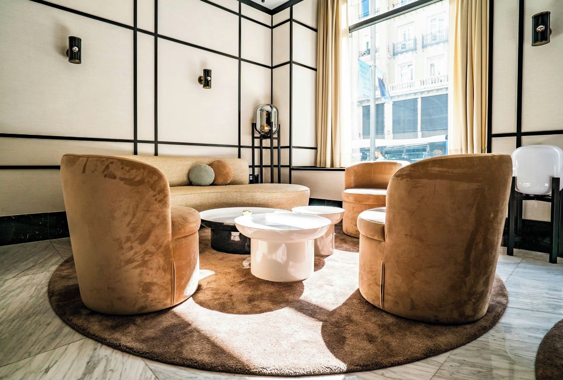 Un área de descanso moderna con un sofá, dos sillones, una mesita de centro y un tapiz estampado.
