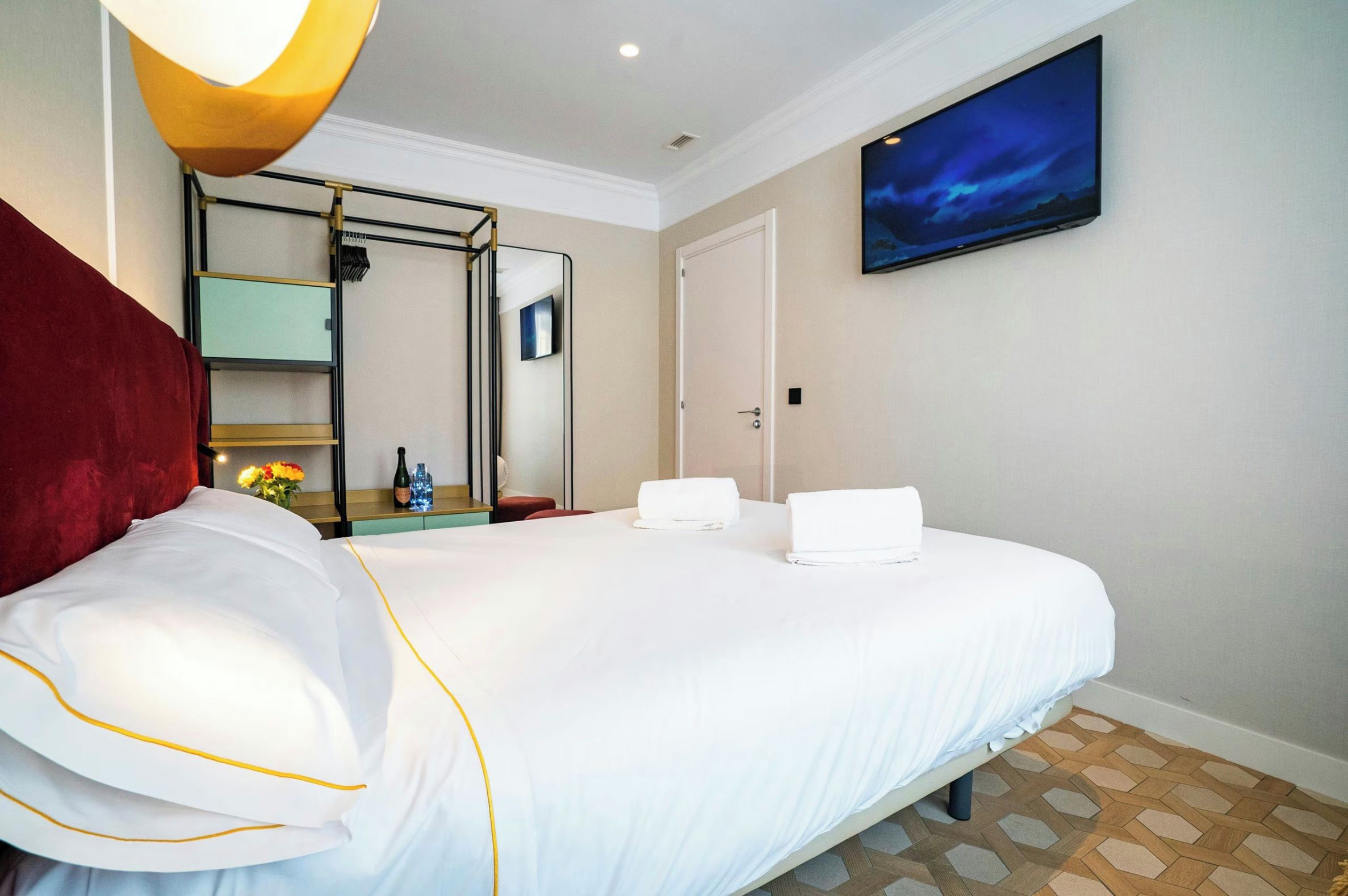 Habitación de hotel con cama, espejo, televisor y vista al cielo nocturno.