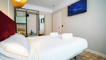 Habitación de hotel con cama, espejo, televisor y vista al cielo nocturno.