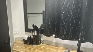 Eine kleine Küche mit Kaffeemaschine, Spüle und einer Uhr an der Wand.
