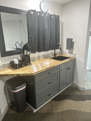 Een badkamer met een wastafel, spiegel en een klok aan de muur.