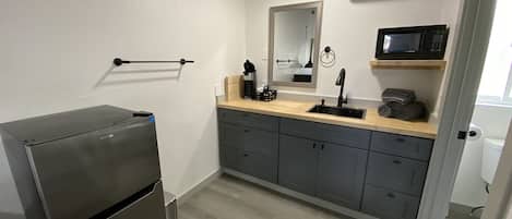 Une petite cuisine équipée comprenant un réfrigérateur encastré, un four à micro-ondes et un évier.
