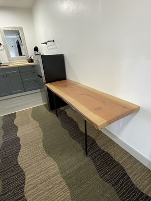 A room with a wooden bench, a kitchen area with grey cabinets, and a patterned carpet. - 2 Queen Beds Near Silverwood Theme Park | Room 9 (Athol)