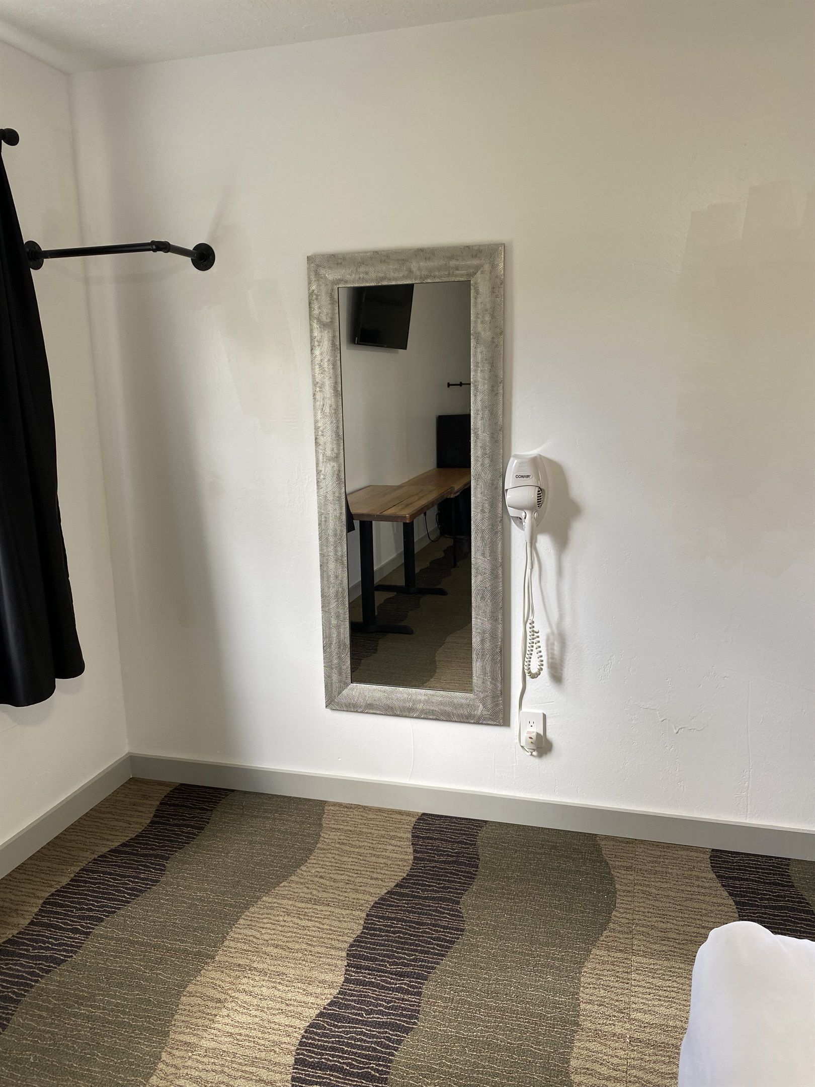 A room with a mirror, a hairdryer, and a bench.