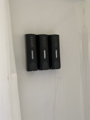 Three black wall-mounted dispensers labeled 'HAIR,' 'BODY,' and 'COND' on a white wall. - 2 Queen Beds Near Silverwood Theme Park | Room 9 (Athol)