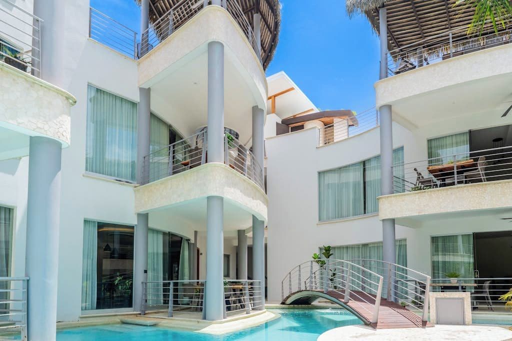 Un hotel moderno con piscina, balcones y una zona exterior cubierta.