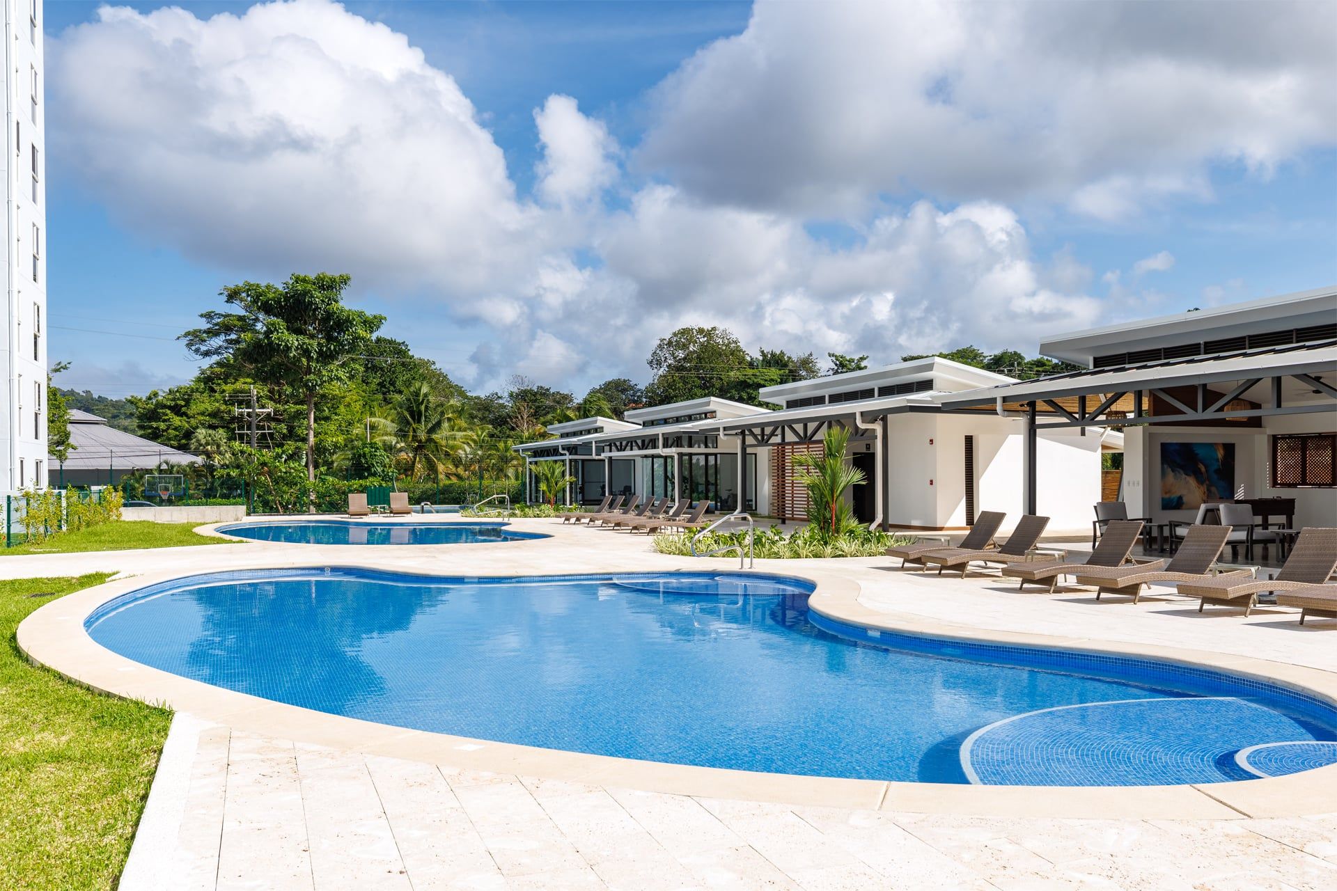 A swimming pool area with multiple pools, lounge chairs, and covered seating areas.