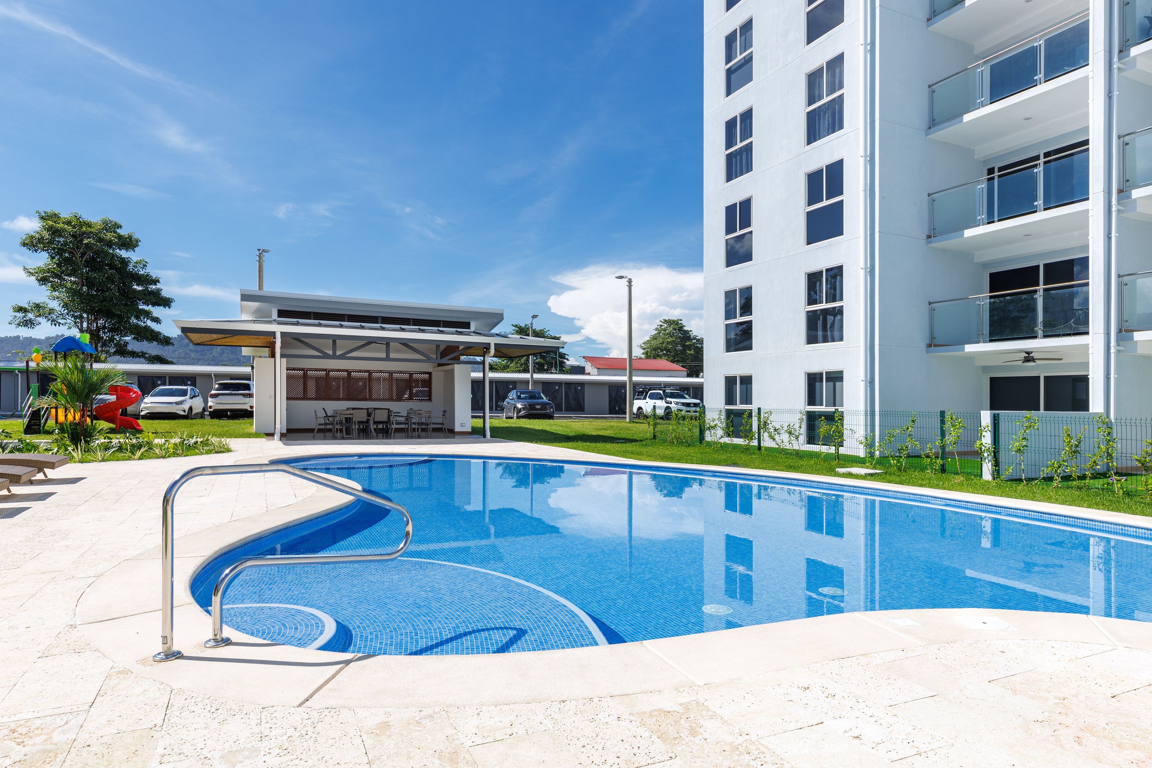 Un edificio moderno con piscina, zona de estar exterior y un área cubierta pequeña.